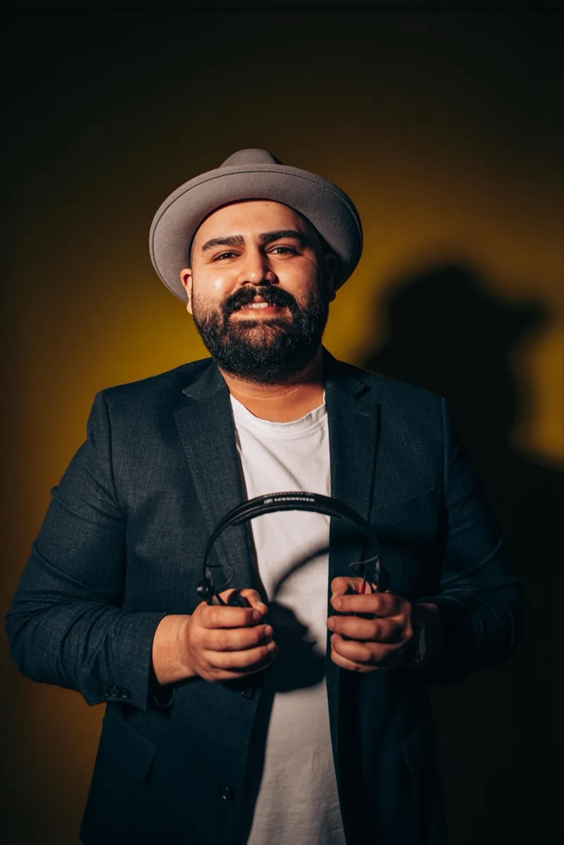 DJ SAM lächelt am DJ-Pult während einer Feier